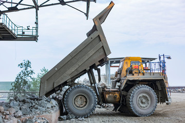 Heavy dump truck empty just unloaded granite into huge rock crusher