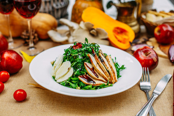 Autumn table setting with pumpkins. Thanksgiving dinner. Salad with chicken breast, cheese and arugula