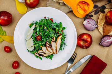 Autumn table setting with pumpkins. Thanksgiving dinner. Salad with chicken breast, cheese and arugula