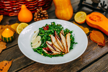 Autumn table setting with pumpkins. Thanksgiving dinner. Salad with chicken breast, cheese and arugula