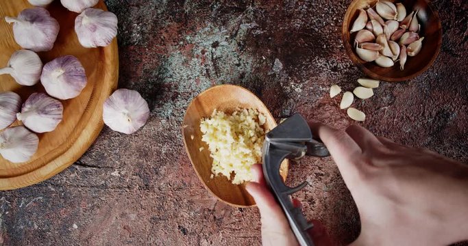 Men hands crushed garlic in masher.