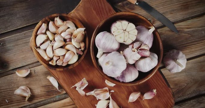 Heads and cloves of garlic in bowls on the cutting Board slowly rotate.