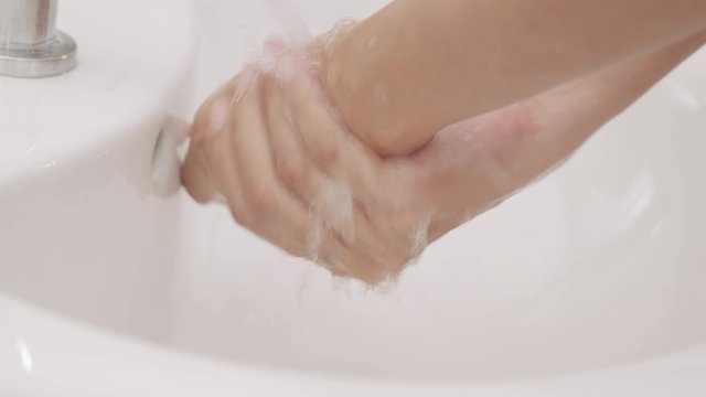 Asian women Cleaning hands with white soap bubbles at Sinks in the bathroom. Hand washing demonstration for virus protection. Concepts of hygiene and prevention of covid 19. Close up of woman hand
