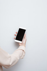 Closeup shot of a woman hold on mobile phone. Girl's hand holding a modern smartphone. Blank screen to put it on your own webpage or message.