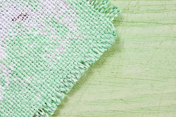 Closeup texture of a roughly painted white and light green canvas lying on a wooden surface. Background for fabric texture. Universal background.