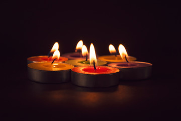Group of colorful candles burning in the dark