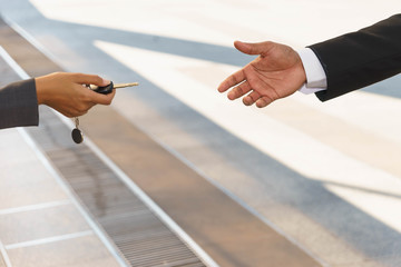 Saleswoman is handing car key to a man. 