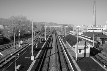 Empty railroad tracks and station at dawn. Black and white.
