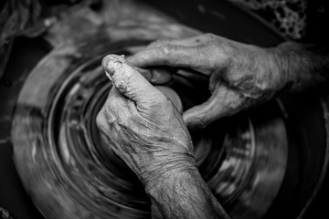 Hands of the potter. The potter makes pottery dishes on potter's wheel. The sculptor in workshop makes clay product closeup