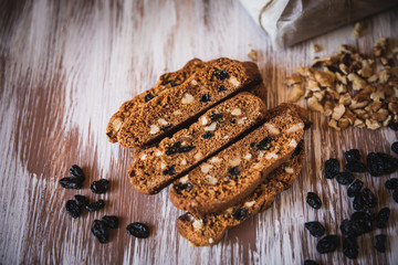 Italian biscotti cookies with walnuts and raisins, shot on a dark wooden background. Background for cooking and home baking.