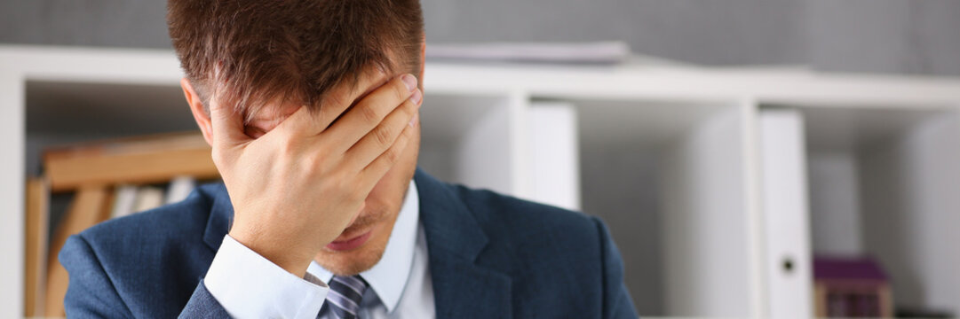 A man experiences stress and a headache in the workplace experiences negative emotions from paper red tape trouble personality career growth lack of knowledge palmface