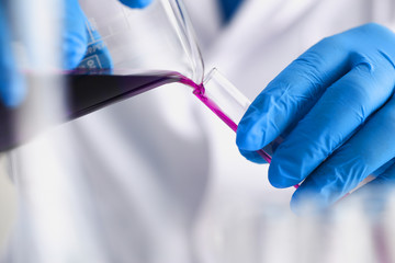 A male chemist holds test tube of glass in his hand overflows a liquid solution of potassium...