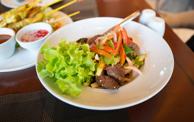Spicy salad with meat on the dinning table and side dishes