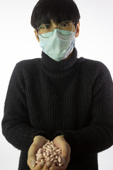 Portrait of asian man. Chinese guy in medical mask against 2019-nCov and glasses with hands full of medications. White background. Prevent spread of corona virus. Chinese coronavirus outbreak concept.