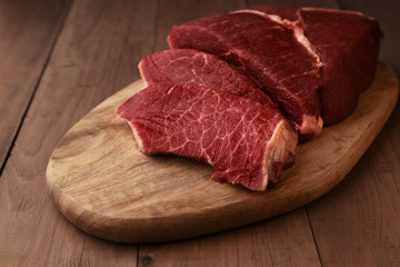 Angus beef meat on a wood board. Raw red meat on wooden table. Textured beef meat with with white...