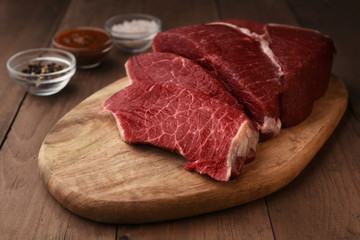 Raw beef meat with seasoning on a wood board. Sliced red meat ready to preparing. 