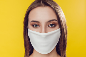 Woman wearing face protective mask on face against Coronavirus on the yellow background.