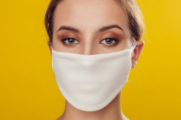 Woman wearing face protective mask on face against Coronavirus on the yellow background.
