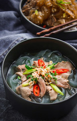 Asian cuisine, Vietnamese pho bo soup in a black plate on a dark background