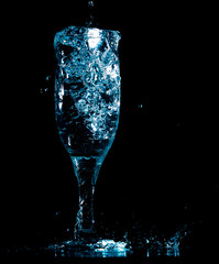 Splashes and drops of water in a glass are isolated on a black background.
