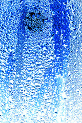 Drops of water on blue glass as an abstract background