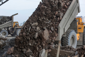 Heavy dump trucks unload granite into huge rock crusher