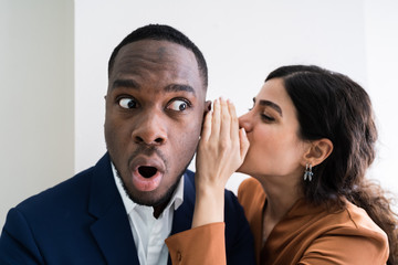 Businesswoman Whispering Into Male Partner's Ear