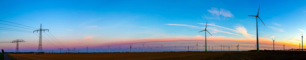 Obraz premium viele Windräder bei Sonnenuntergang stehen auf einem Feld und produzieren Strom
