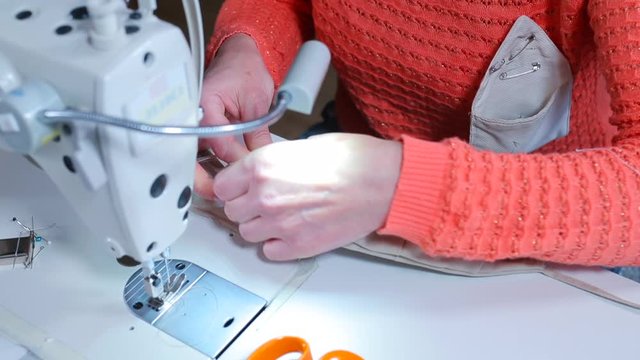 A seamstress sews fabric on a sewing machine on a face mask. Employment in self-isolation. Valant work.