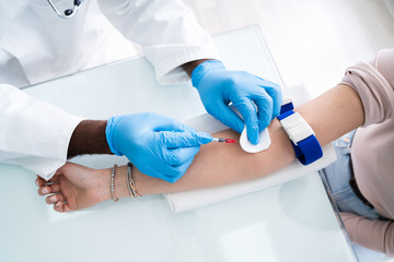 Doctor Injecting Patient With Syringe To Collect Blood