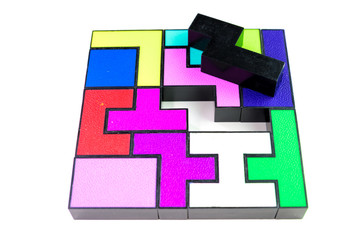 Multi-colored puzzle made of plastic blocks, that's missing one piece, isolated on white background