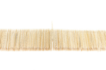Large number of toothpicks lined up in a long row, with one sticking out, isolated on white background