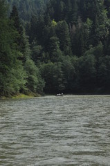 Rafting on the Dunajec River in the Pieniny National Park on wooden folding shuttles tied with a rope. Rafters paddling on a rapid stream with a rocky bottom and strong river current.