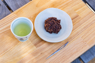 sticky rice cake coated in smashed sweet beans on a pottery tray.
