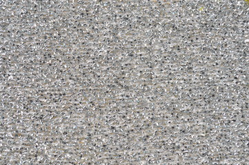 Many pumpkin seeds are gathered together on a white container.