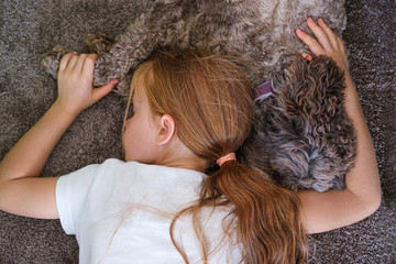 young girl lying close to her dog for comfort