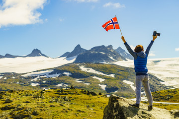 Tourist with camera and flag in Norway mountains