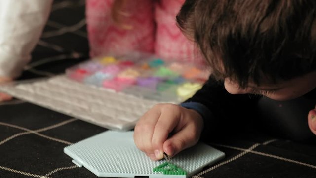 child plays with perler beads. fine motor development
