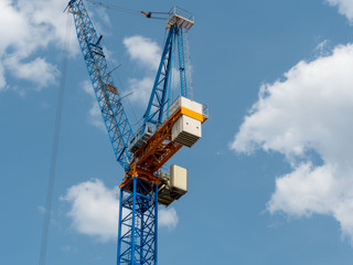 Detail of a crane at a construction site, blue sky with clouds.