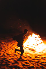 Man dancing around campfire at night