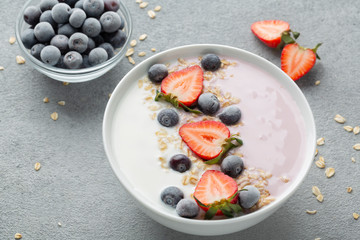 Breakfast with muesli, berry smoothies and coconut yogurt topped with fresh strawberries and blueberries. The concept of healthy eating. 