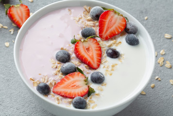 Breakfast with muesli, berry smoothies and coconut yogurt topped with fresh strawberries and blueberries. The concept of healthy eating. 