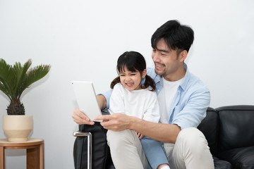 A pair of young Asian father and daughter are using tablet in the living room