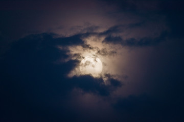 Super moon in a black sky with clouds