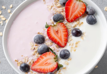 Breakfast with muesli, berry smoothies and coconut yogurt topped with fresh strawberries and blueberries. The concept of healthy eating.  Close up