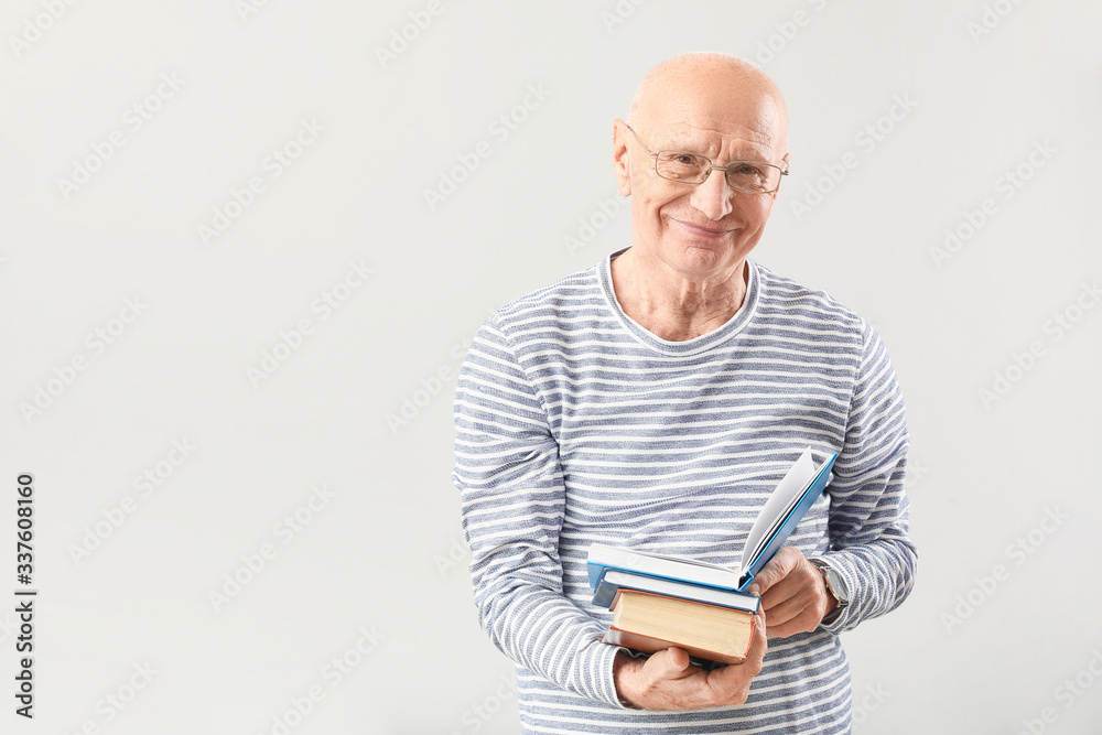 Poster Portrait of elderly man with books on grey background