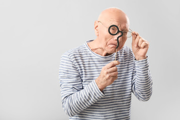 Fototapeta premium Portrait of elderly man with party decor on grey background