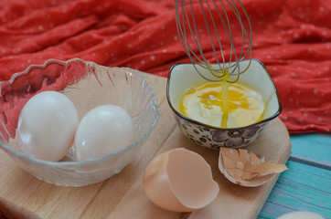 Cooking eggs, eggshells and yolks, whisk on a wooden cutting board. Easter holiday concept