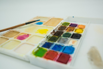 Close up photography of watercolor palette and a brush.