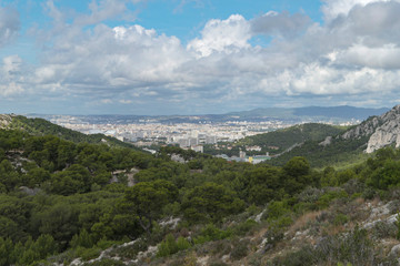 Mountains with green grass and grey rocks near the sea. Blue sky and white clouds.